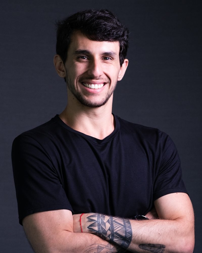 Retrato de Bruno Romano sorrindo, de braços cruzados